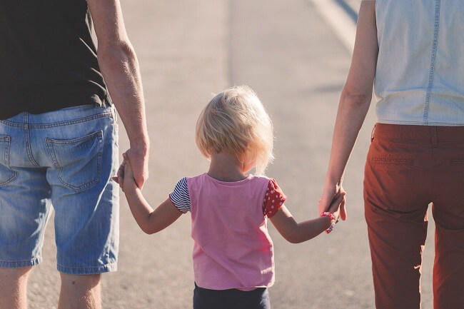 Junges Paar geht mit einem Kind in seiner Mitte spazieren