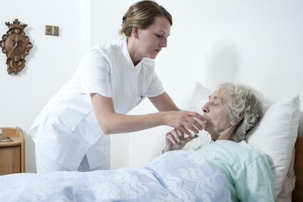 Eine Altenpflegerin kümmert sich um eine bettlägerige Seniorin