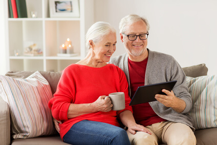 Sympathisches Ehepaar informiert sich auf dem Sofa zum Thema Sterbegeldversicherung