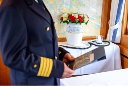 Ein Kapitän der Seebestattungs-Reederei Adler hält eine Seegrabmappe in der Hand